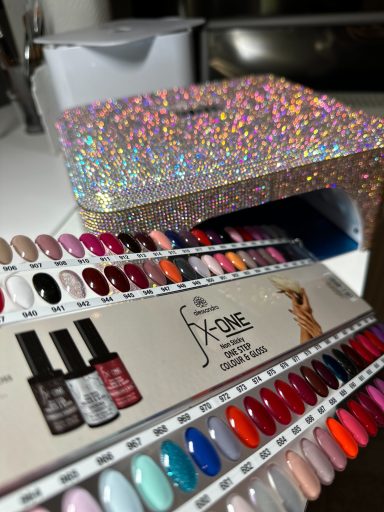 Bunte Nagellacke in einer Palette neben einer glitzernden Aufbewahrungsbox.